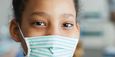 Black teenage girl wearing a blue and white striped mask