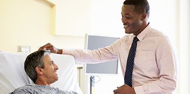 Male physician standing at the bed of a male patient