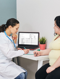 female physician in white lab coat counselling an overweight female wearing black pants and yellow t-shirt