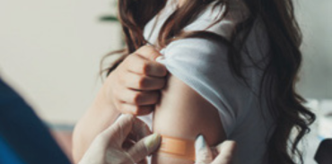 health care practitioner applying a bandage to the upper arm of a female patient