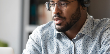 Man wearing earphones and looking at open laptop