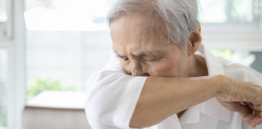 man coughing into his sleeve