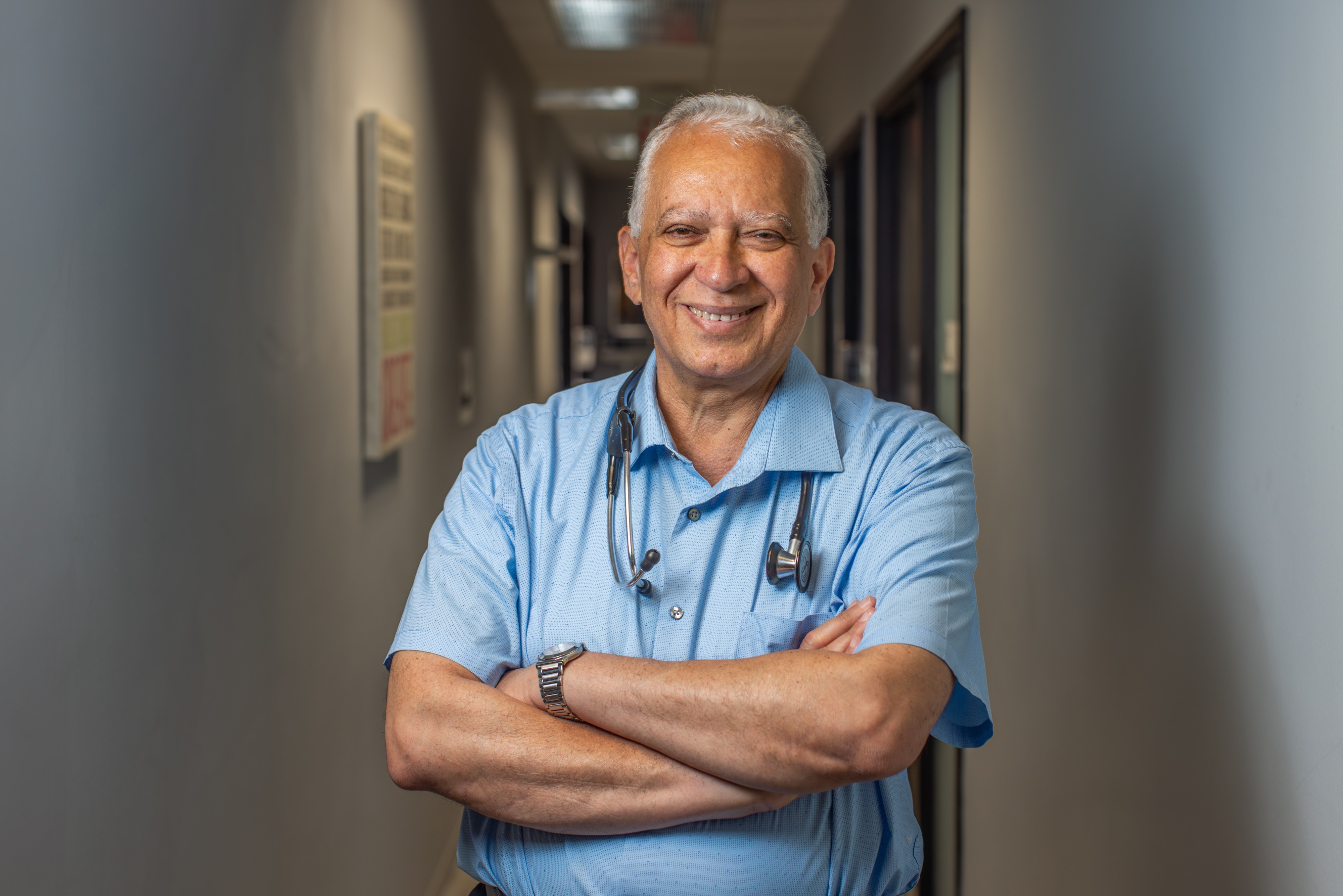 Dr. Gehad Gobran stands in a hallway with his arms crossed.