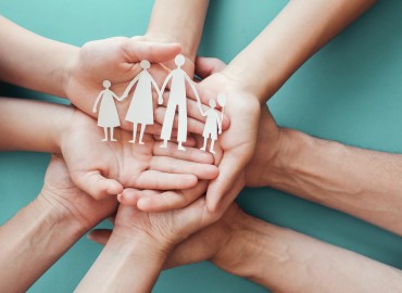 image of many hands, upright, holding a cut out family 