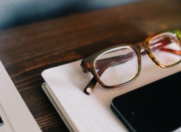 image of a pair of glasses on top of a book with a cell phone