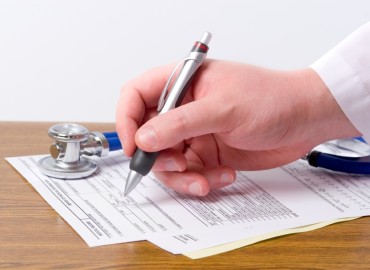 physician filling a prescription on a prescription pad