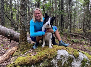 Kerry Copeland sits on log with her dog Beau